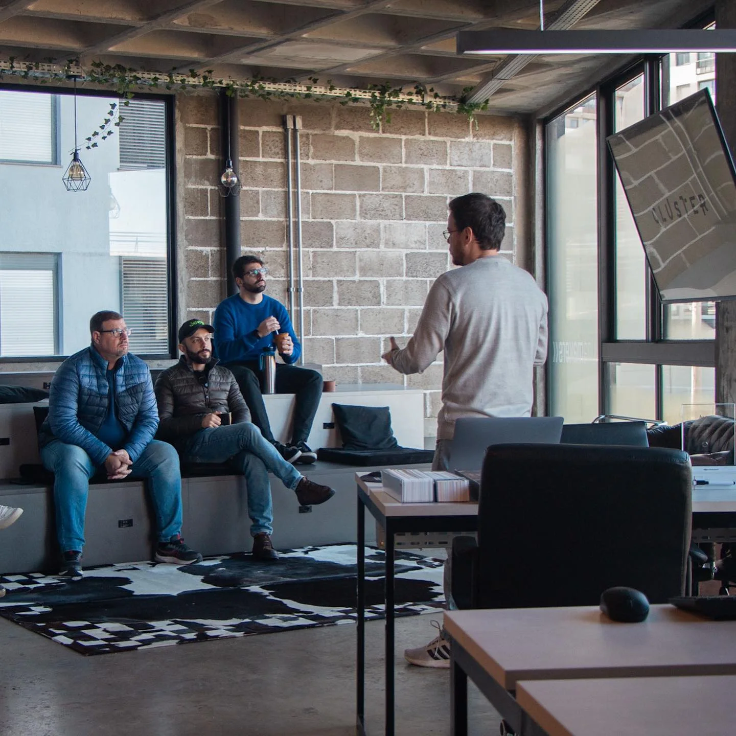 Cluster team members talking in the office, surrounded by sofas, workstations and large windows